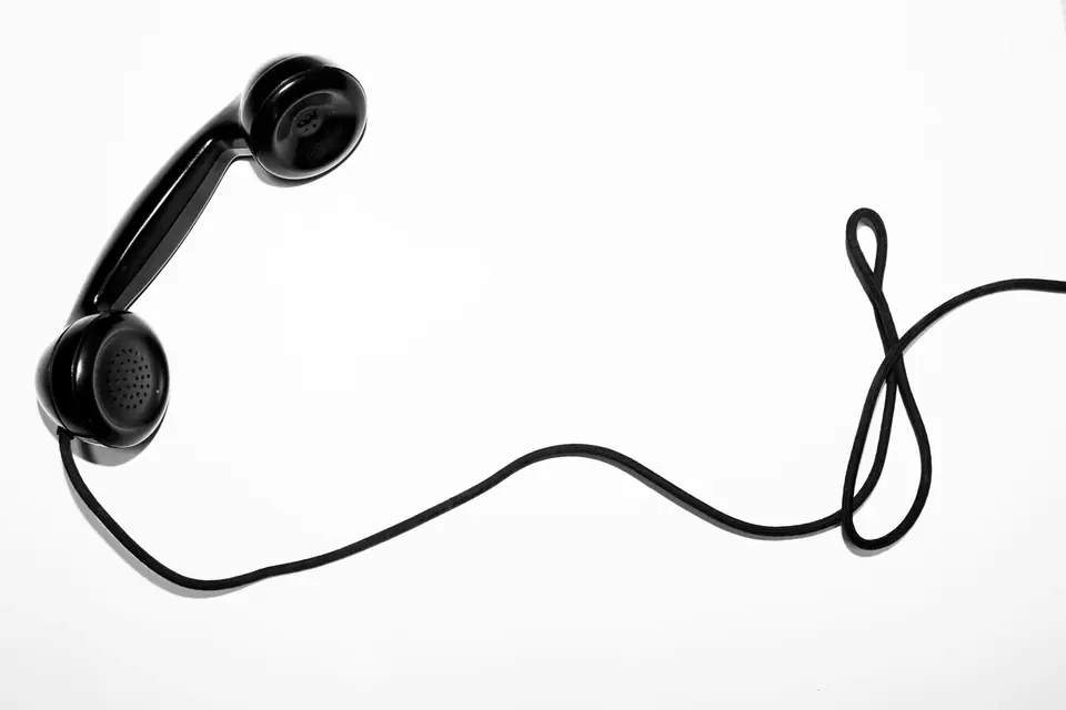 Svart telefonrør med krøllete ledning mot en hvit bakgrunn
